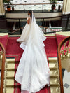 Bride holding the edge of the ELIKA beaded lace veil, emphasizing the intricate craftsmanship.